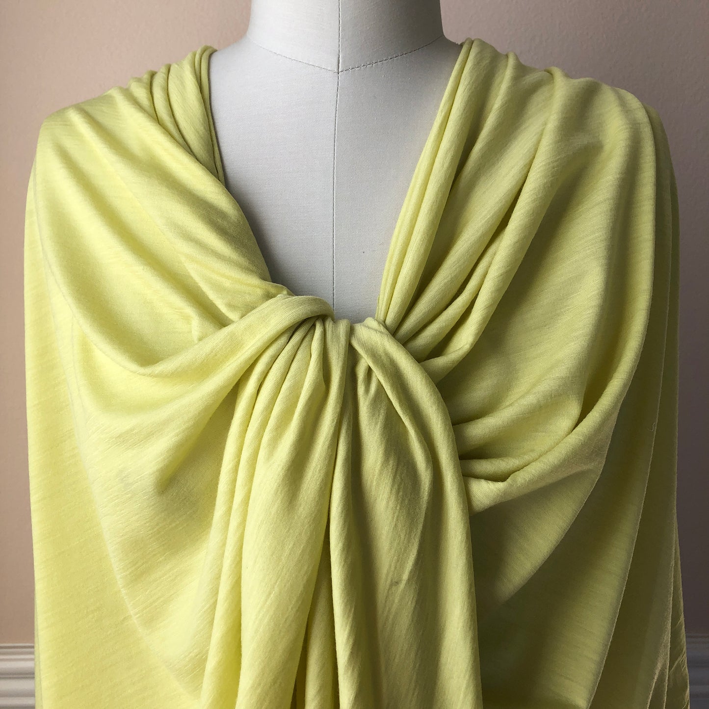 Soft baby duck yellow hue merino wool fabric on a dress form.