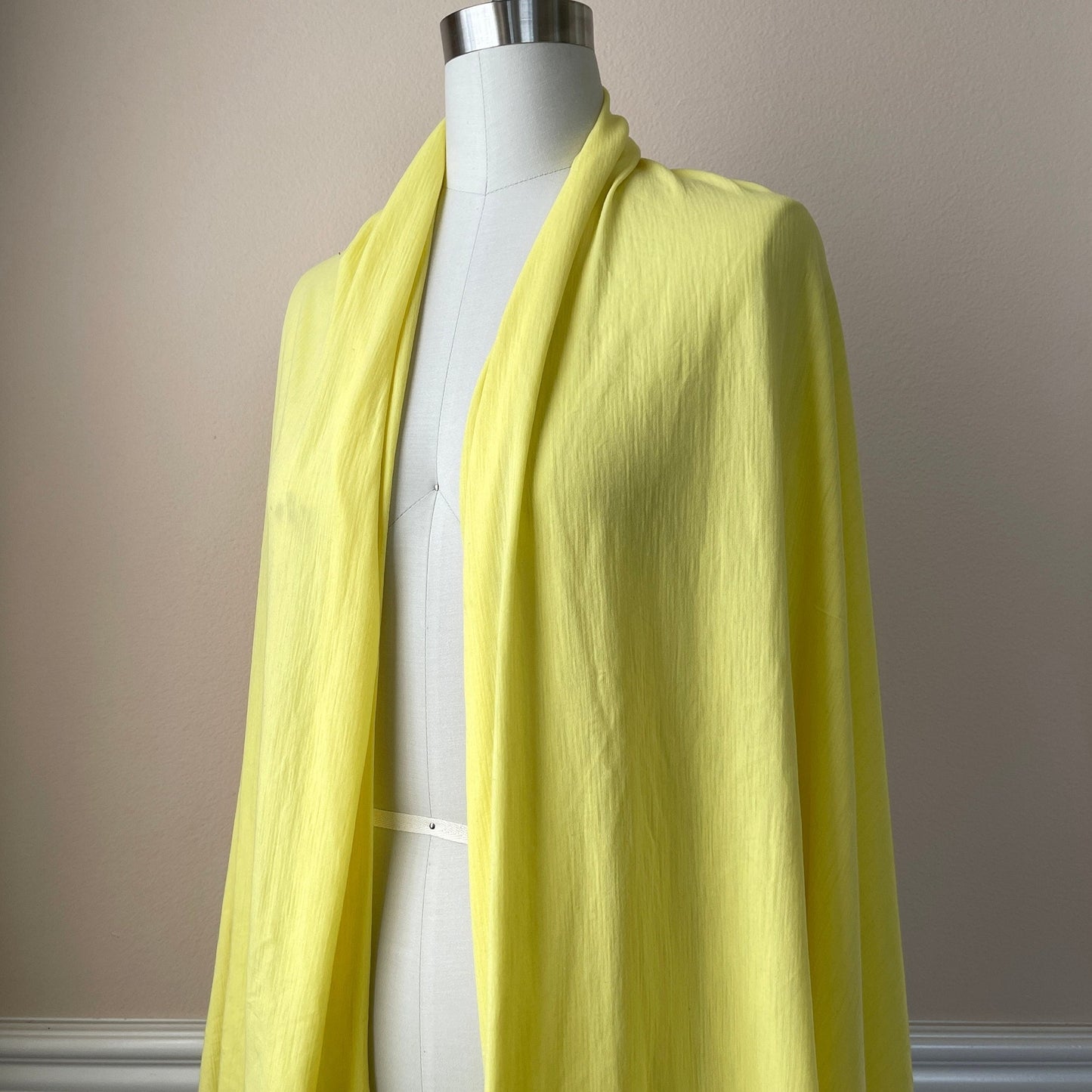 A canary yellow merino wool fabric styled on a female dress form.