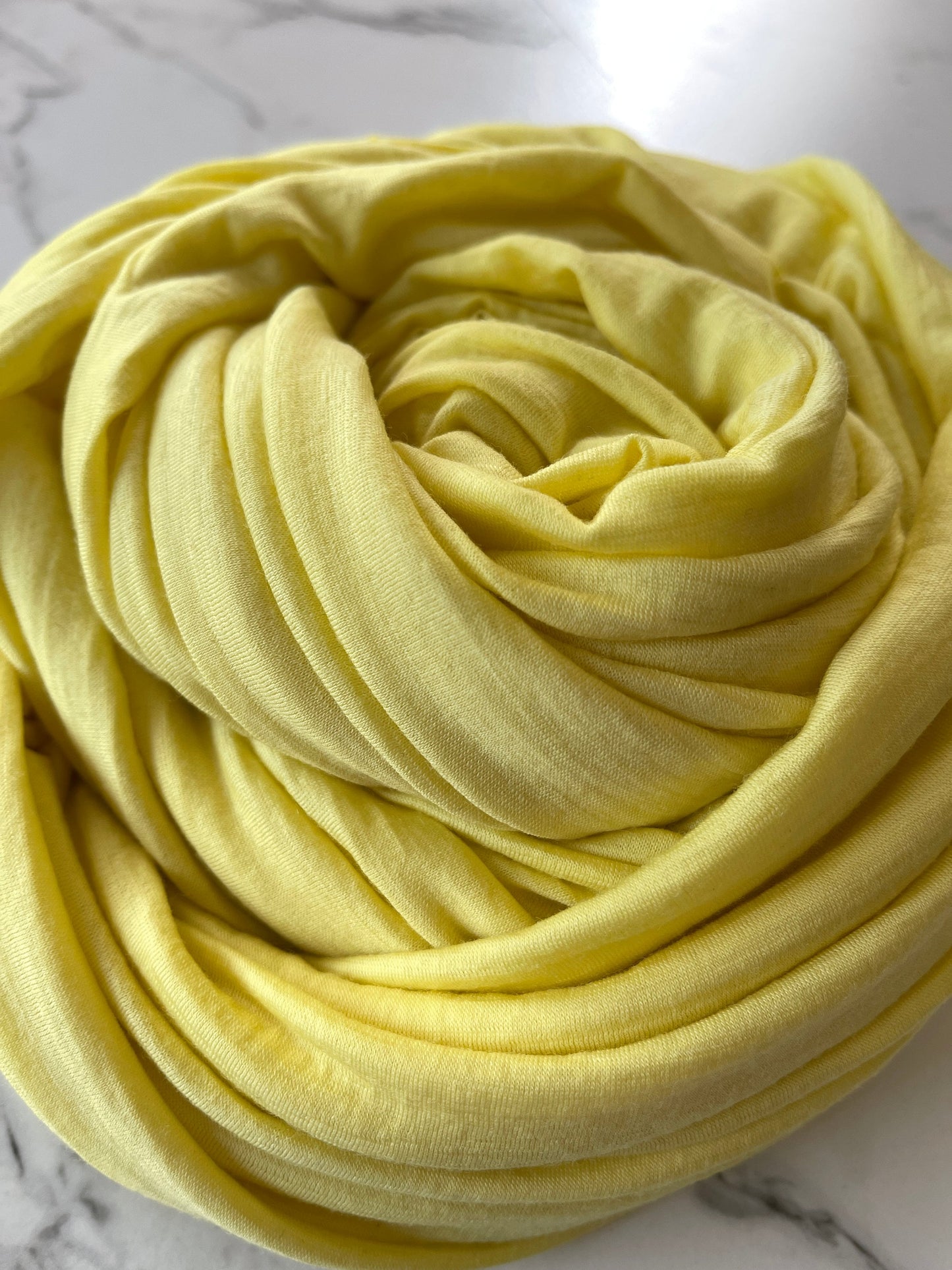 Soft yellow merino wool swirled into a ball.