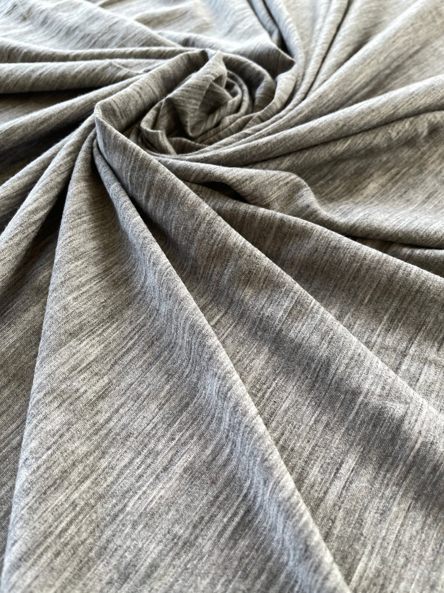 Swirled soft merino wool fabric showcasing high-low effect of heather gray color. 