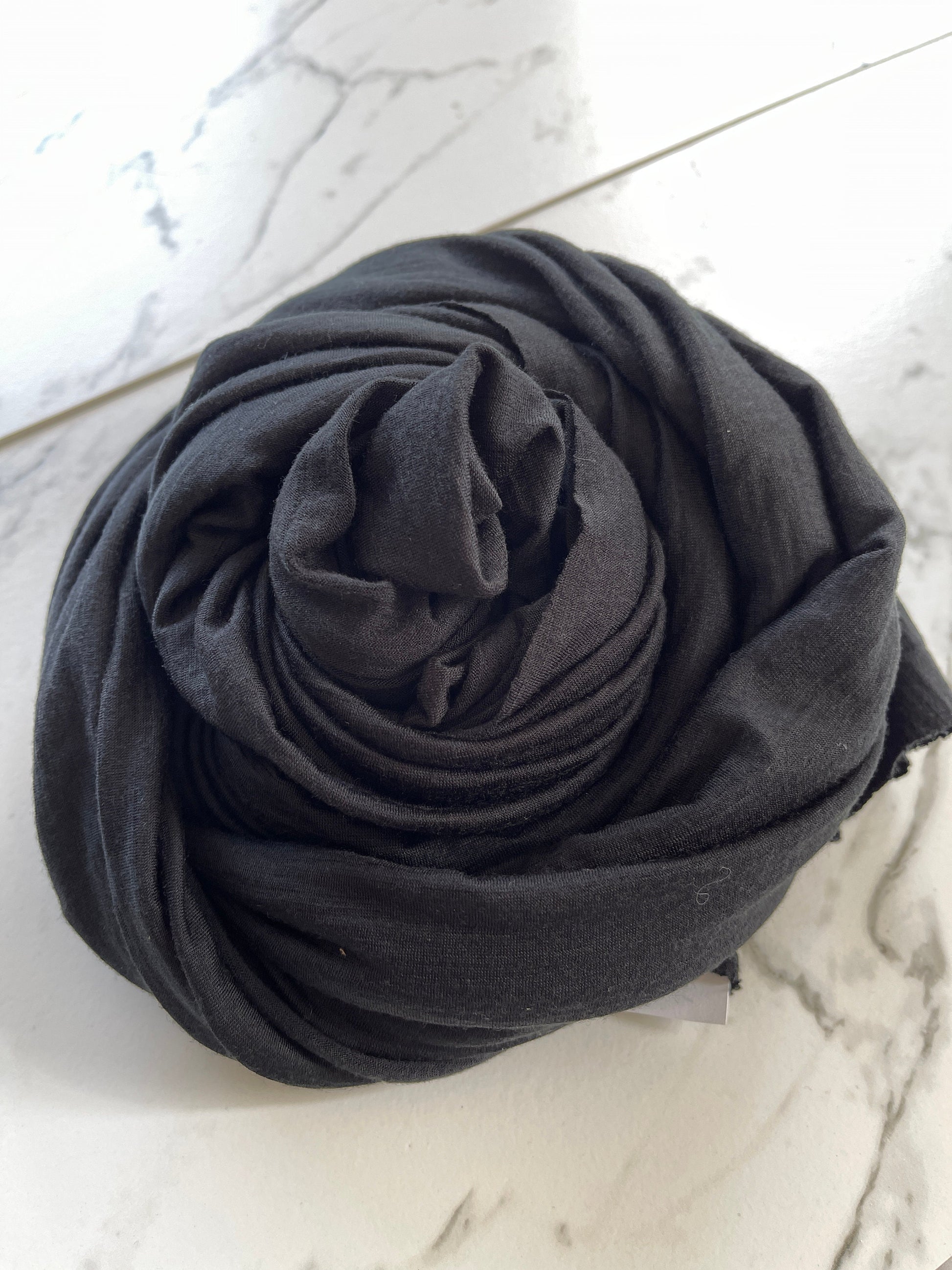 Angle view of swirled true black color merino wool jersey.