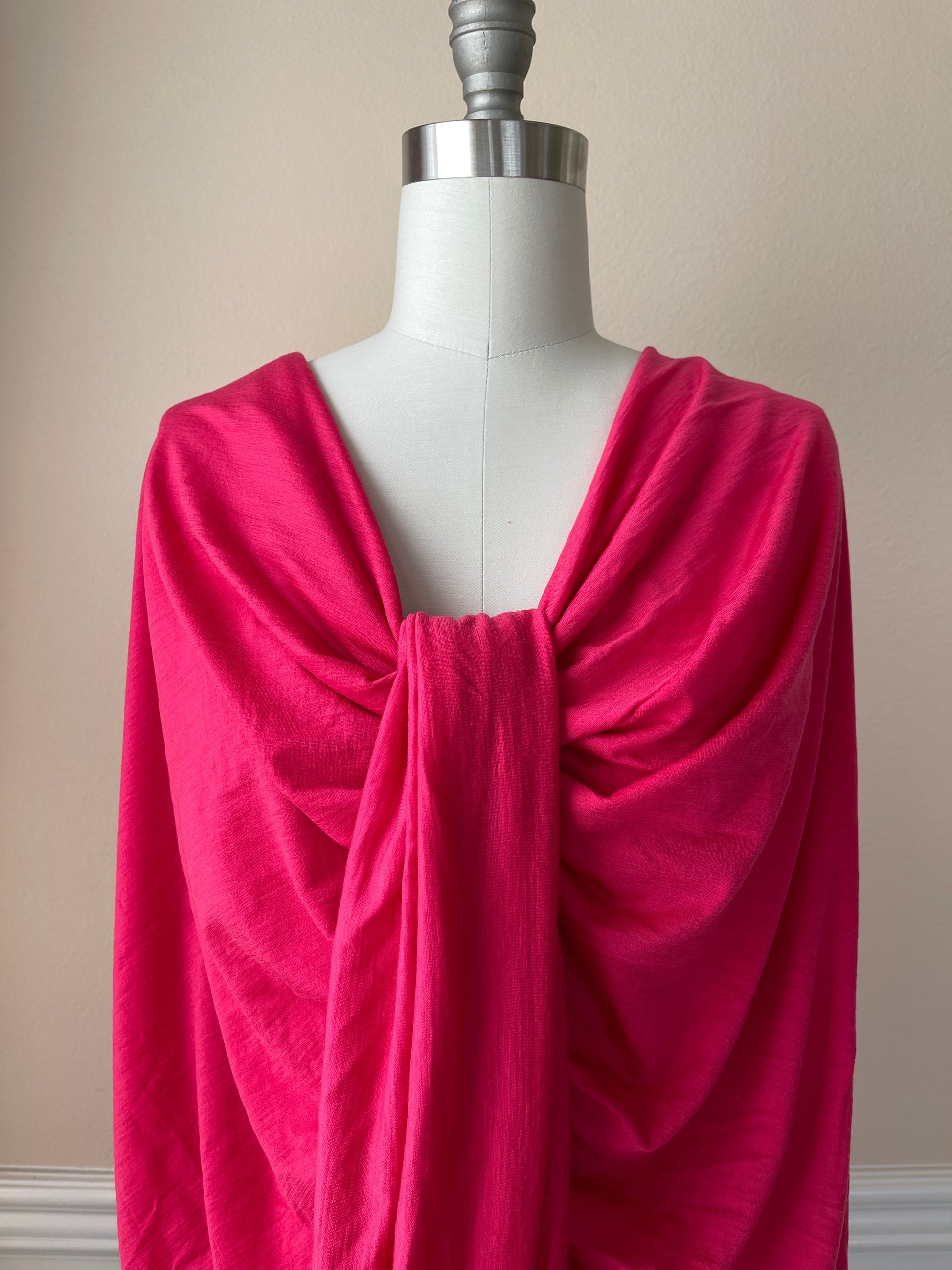 Feminine bright pink merino wool fabric displaying on female dress form.