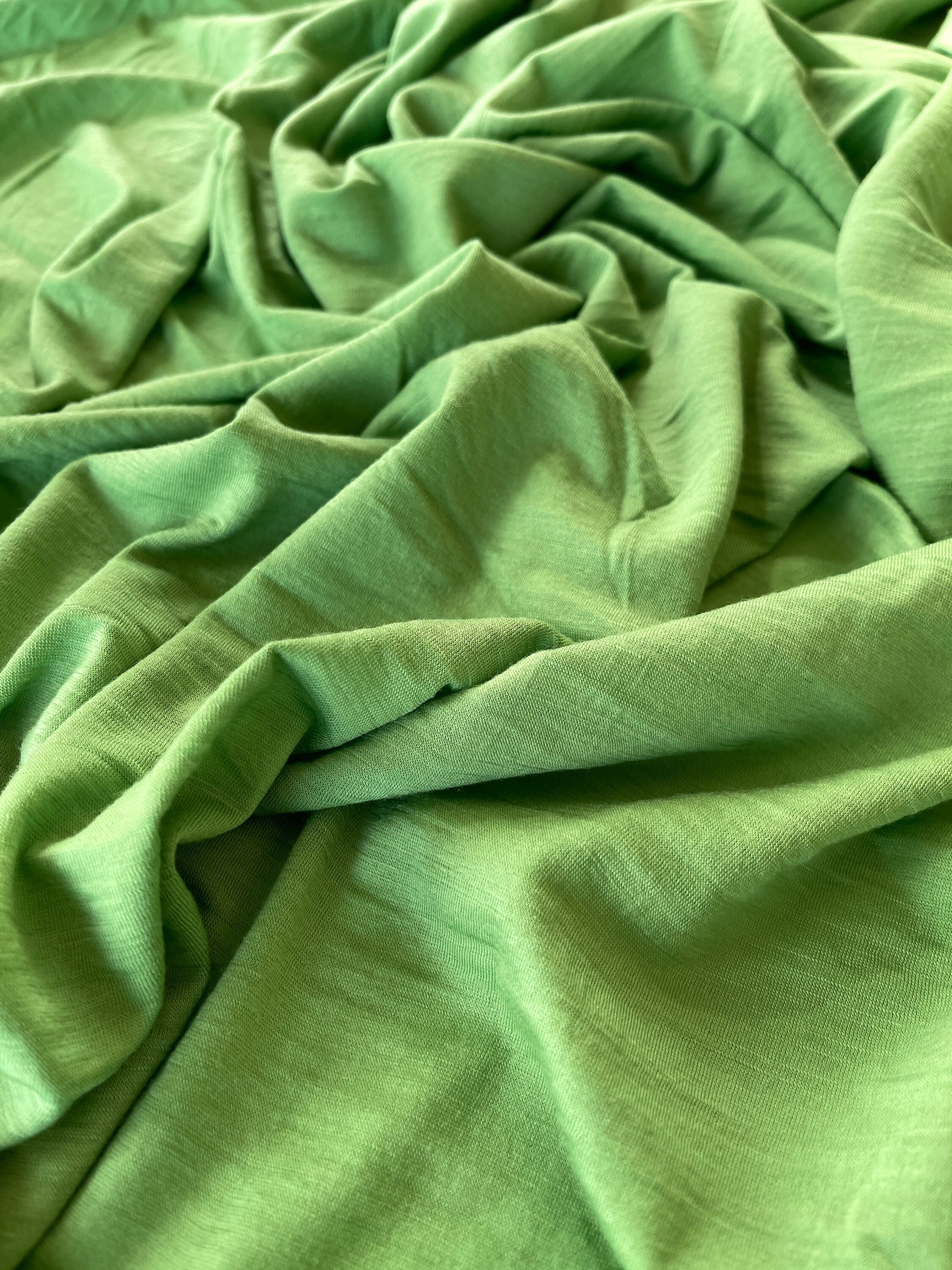 Yarn dyed solid green color merino wool styled flat on table.