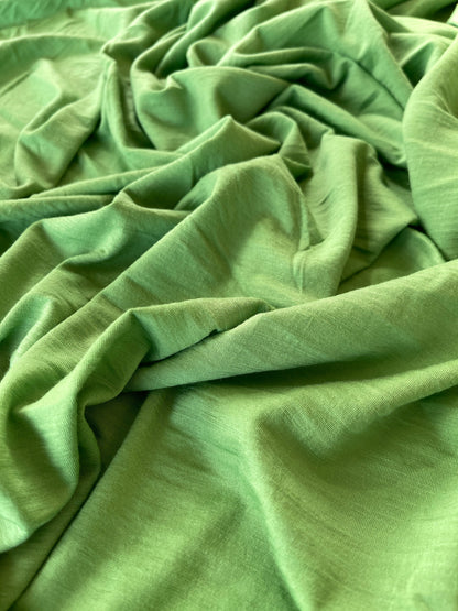 Yarn dyed solid green color merino wool styled flat on table.