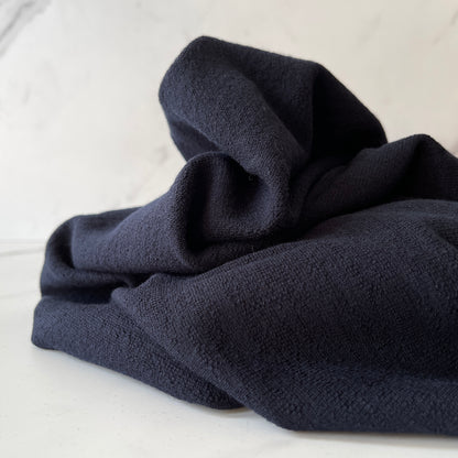 High 4 way stretch merino wool fabric styled on table.