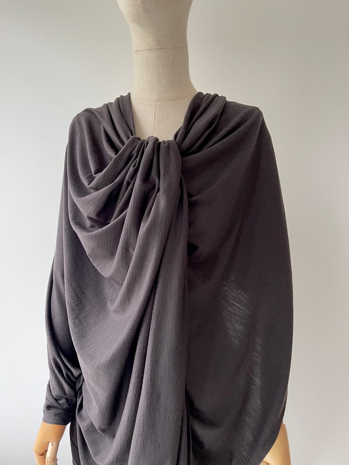 A female dress form with charred color merino wool draped dress.