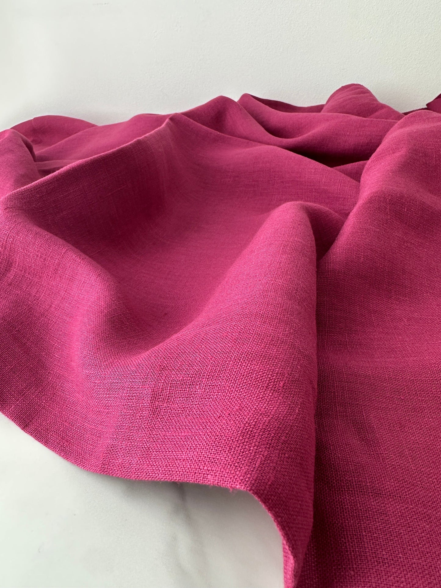 magenta linen fabric roll out and shown on flat surface