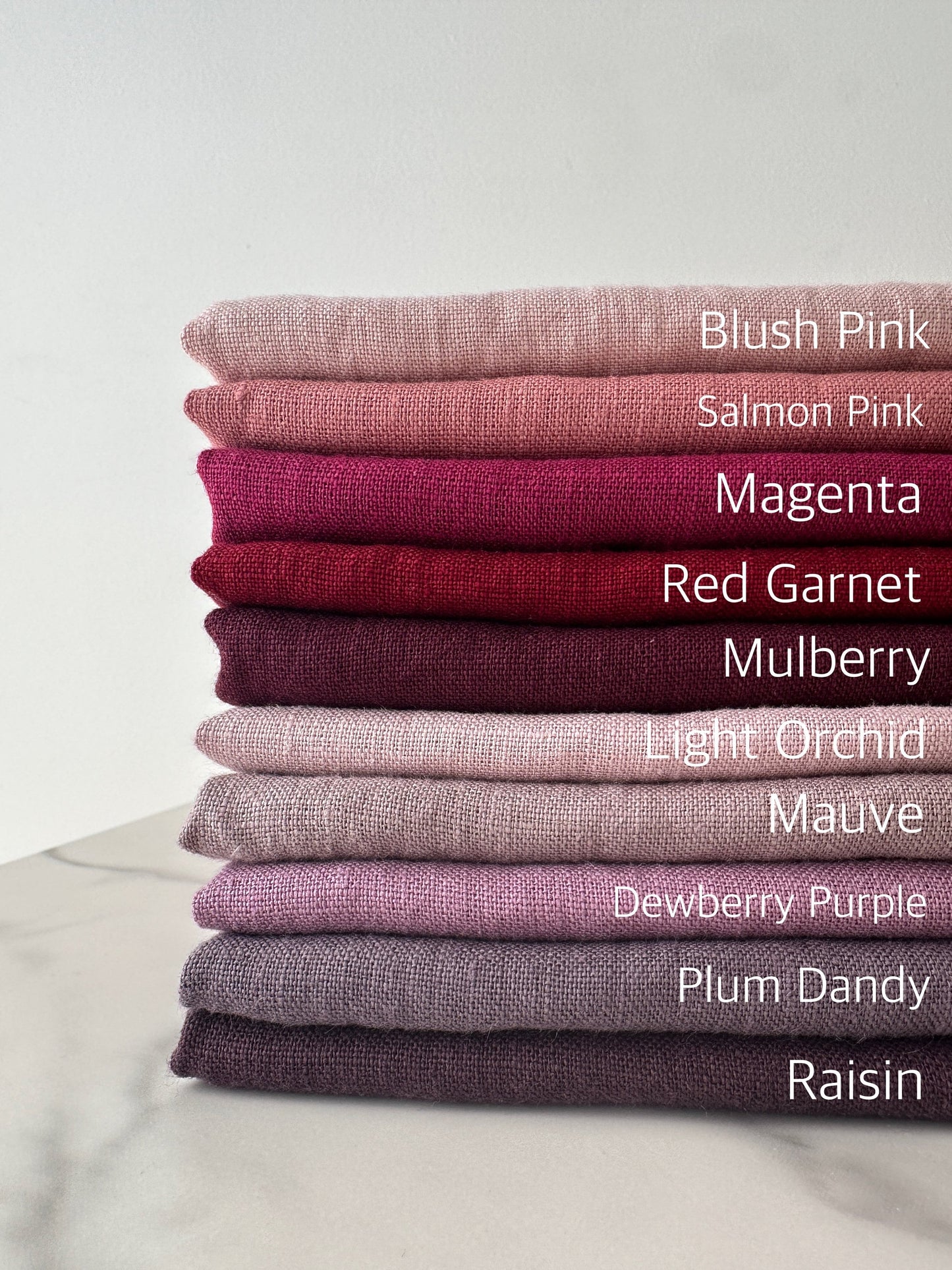 complete color palette of pink and purple European linen fabric folded nicely on flat surface