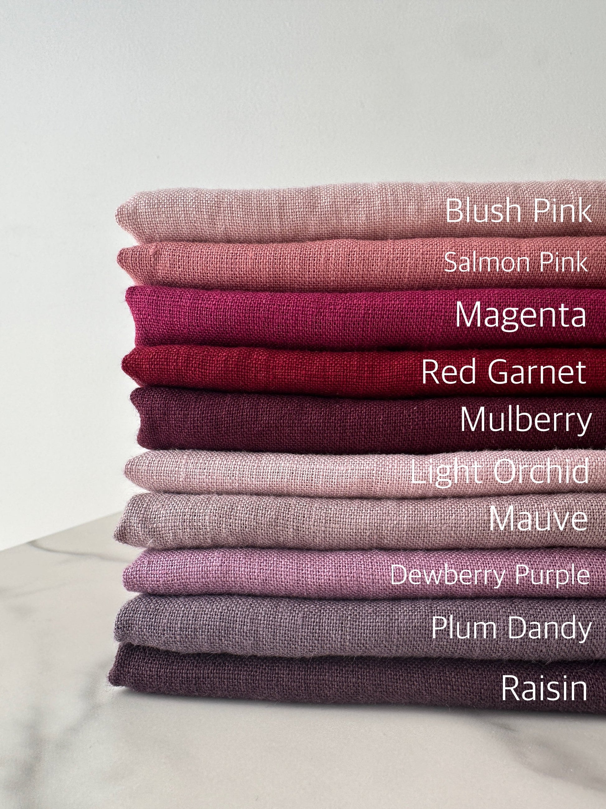 complete color palette of pink and purple European linen fabric folded nicely on flat surface